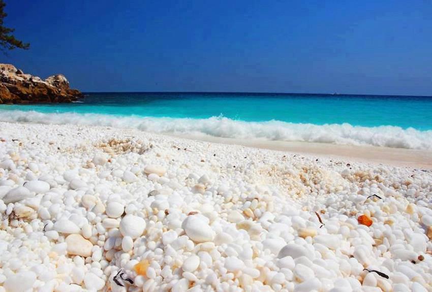 H Παραλία Σαλιάρα στη Θάσο πολλές ομπρέλες στην ακτή και ένα τουριστικό καραβάκι στη θάλασσα