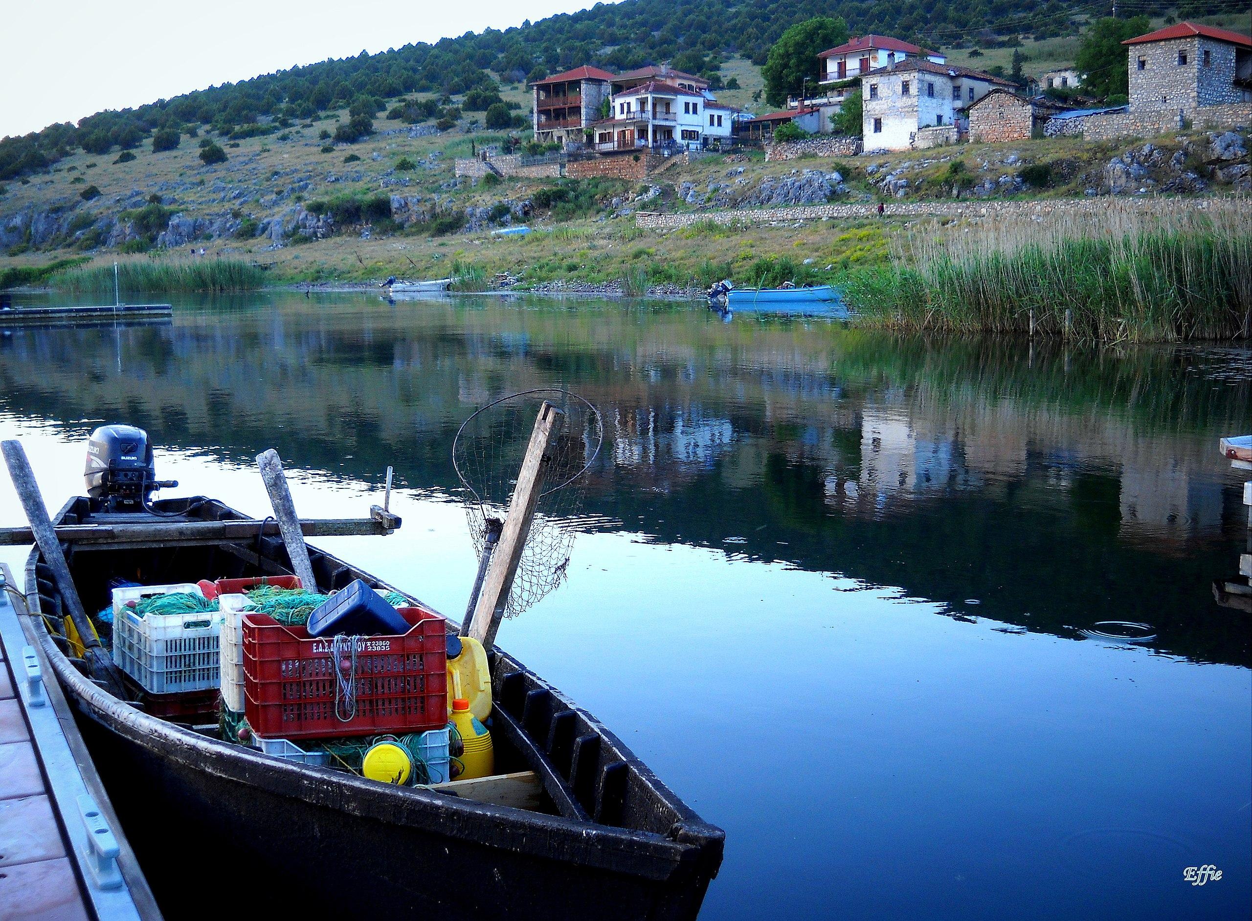 βάρκα στη Μεγάλη Πρέσπα και το χωριό Ψαράδες στο φόντο.